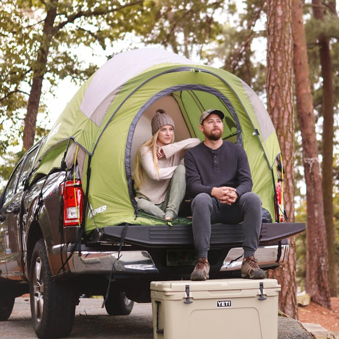 Girl and guy sitting inside a napier backroadz truck tent green and grey